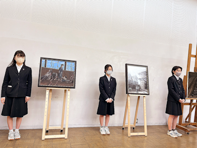 三位學生代表展示他們的畫作。